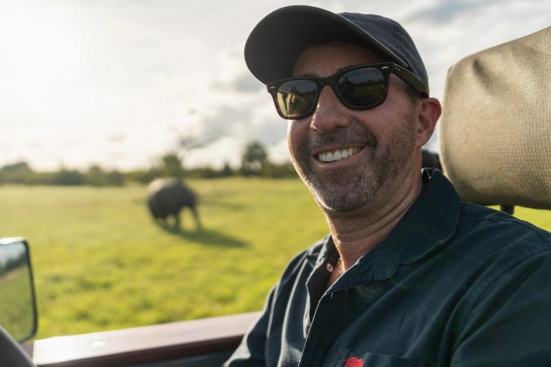 Rhino Africa CEO, David Ryan, photographed sitting in a game drive vehicle with an elephant in the background