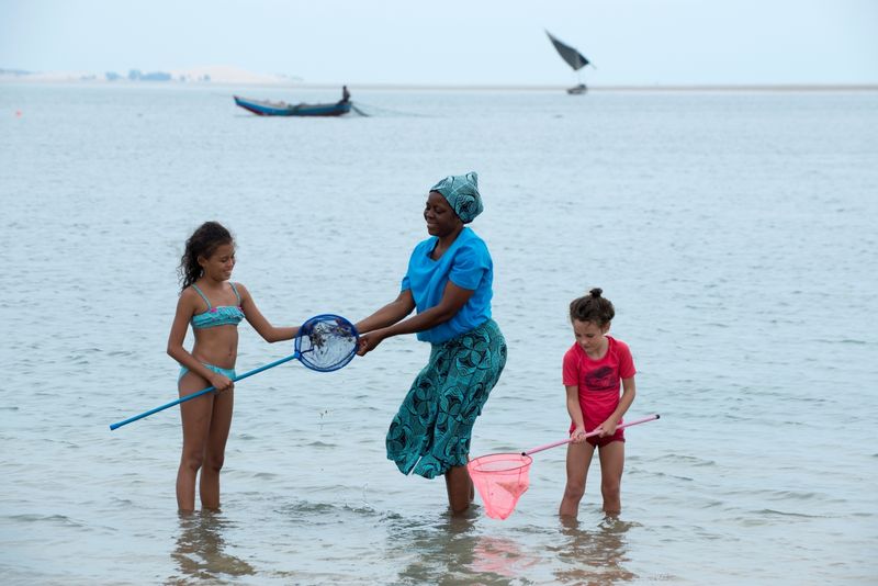 Local woman helping children catch sea creatures in the shallows