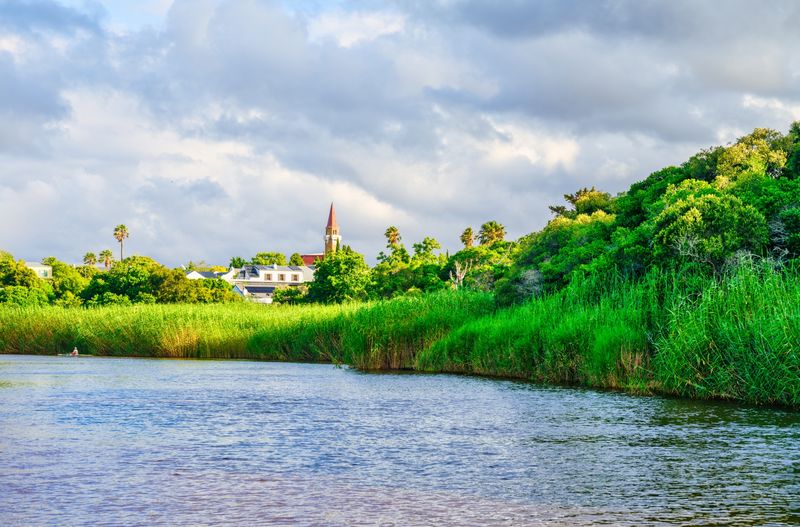 A lush riverbank with heritage buildings in Stanford
