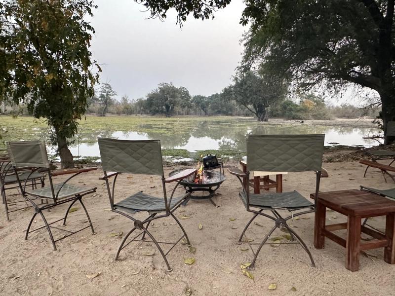 Safari chairs set around a campfire beside the Zambezi River in Mana Pools.