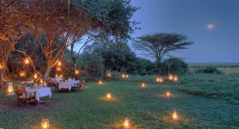 Ein Dinner in der Masai mara am Abend, helle Kerzen leuchten im Gras