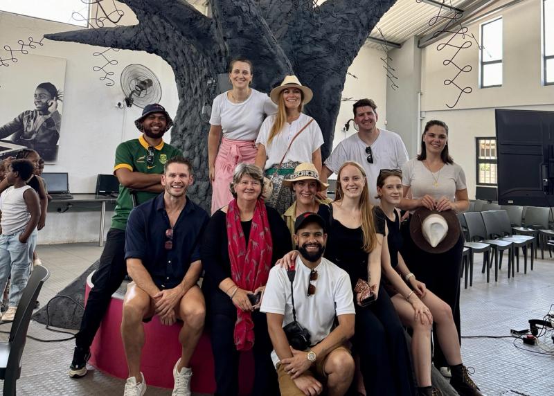 A group of smiling individuals from the Rhino Africa marketing team pose together in front of the striking tree sculpture at GWF, capturing a moment of connection and shared purpose.