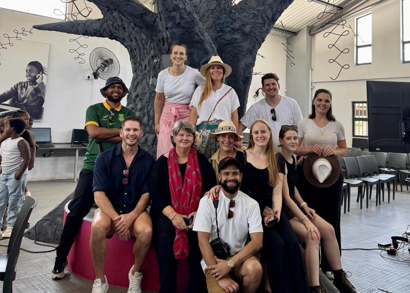 A group of smiling individuals from the Rhino Africa marketing team pose together in front of the striking tree sculpture at GWF, capturing a moment of connection and shared purpose.