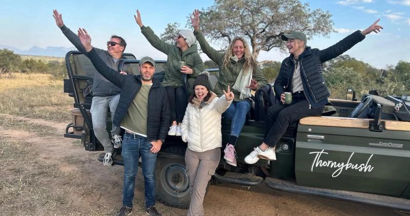 A group of guests pose in front of a game drive vehicle while on a South Africa safari in the Kruger