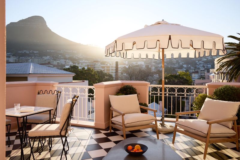 A sunlit terrace with cushioned chairs and mountain views at one of the luxury hotels in Cape Town
