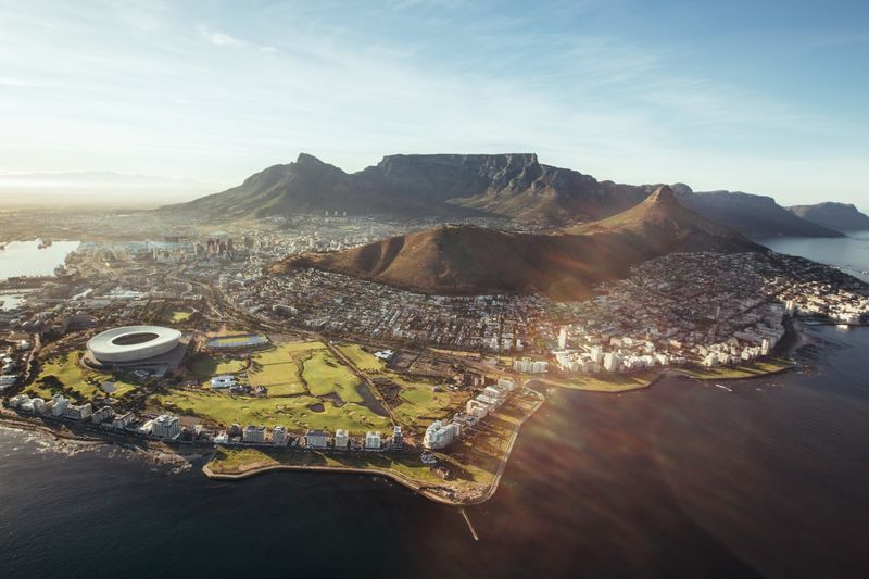 Mauritius and safari holiday, An aerial view of Cape Town reveals the city’s stunning coastline, lush green spaces, and the iconic Table Mountain towering over the skyline.