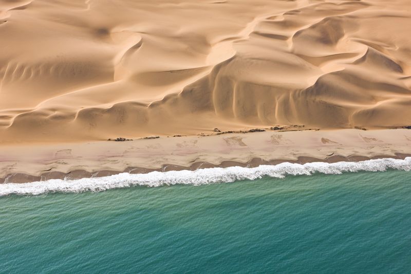 Red sand dunes stretching toward the Atlantic Ocean; ideal for a digital detox in Namibia.