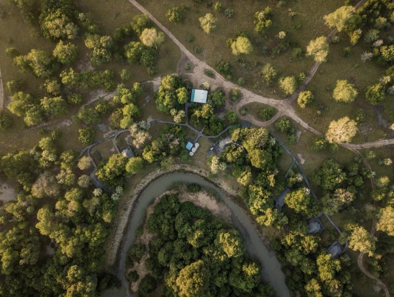 An aerial view shows a safari camp set along a winding river amid woodland and open clearings in Gorongosa.