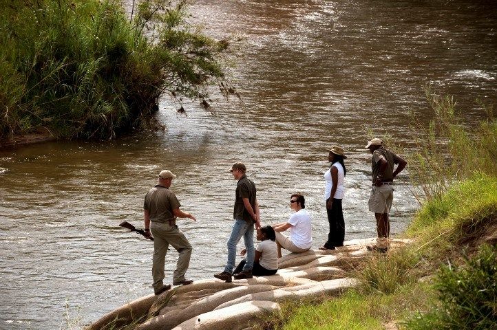 Safari-Urlauber auf einer Buschwanderung im Lion Sands Game Reserve an einem Fluss