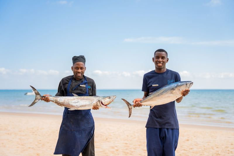 Smiling staff holding two massive fish