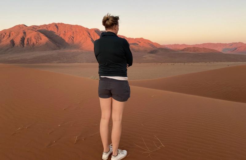 Peggy overlooking the mountains and sand dunes of the Namib Desert at sunset near Sossusvlei, Namibia.
