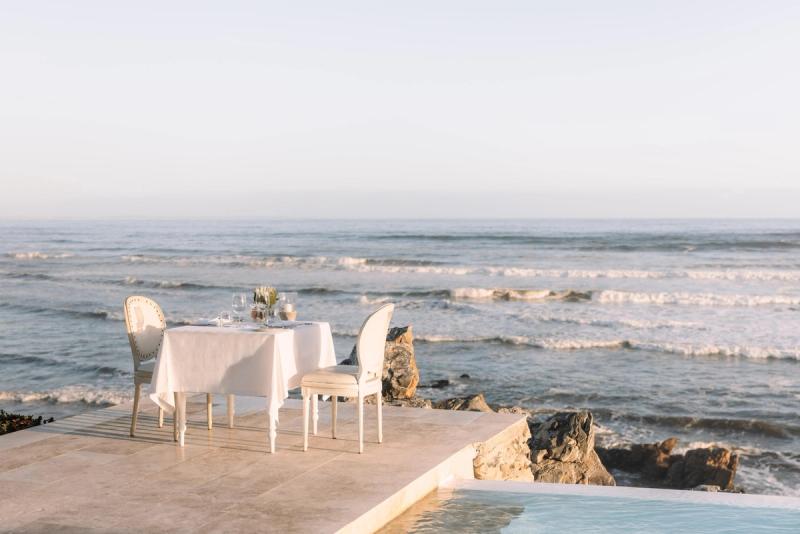 A private dining table set for two overlooks the ocean, offering a peaceful and romantic setting for a babymoon safari.