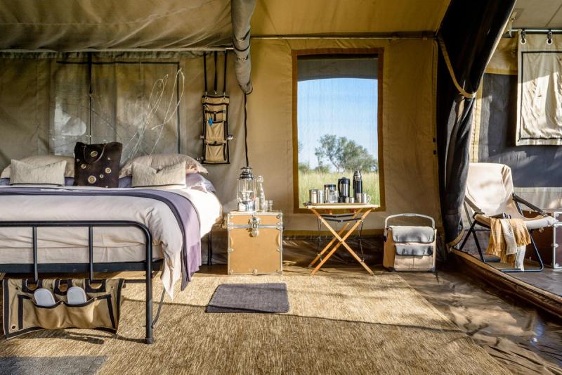 The interior of one of Singita’s mobile tented camps reveals a king-sized bed, canvas furnishings, and curated comforts with views into the bush.