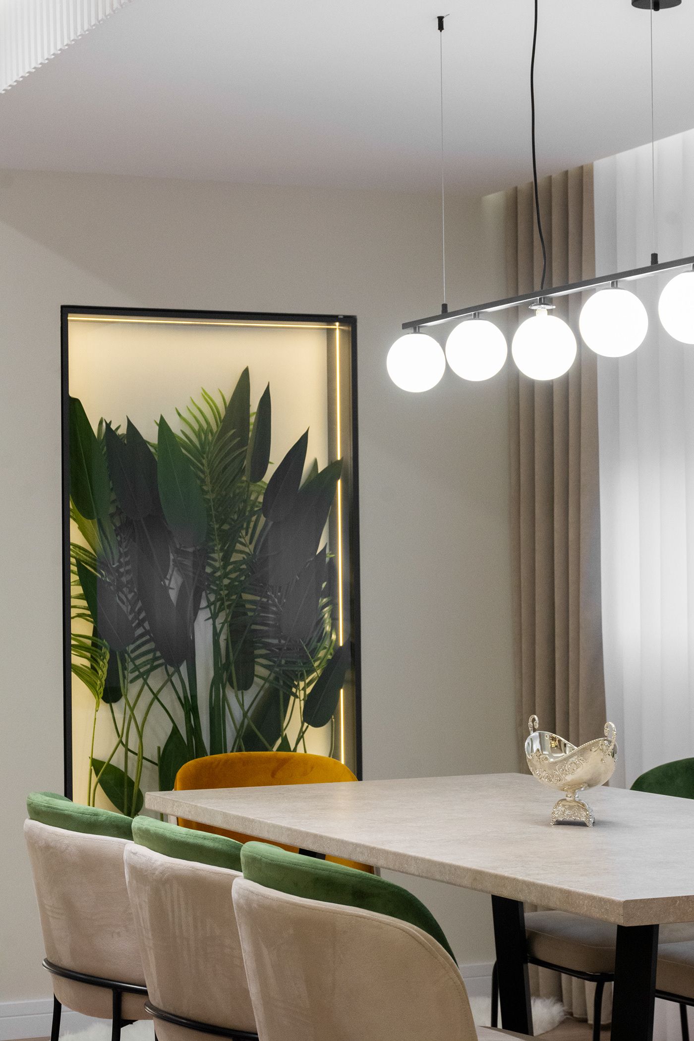 Dining table with green chairs and a backlit plant wall, apartment in Gostivar