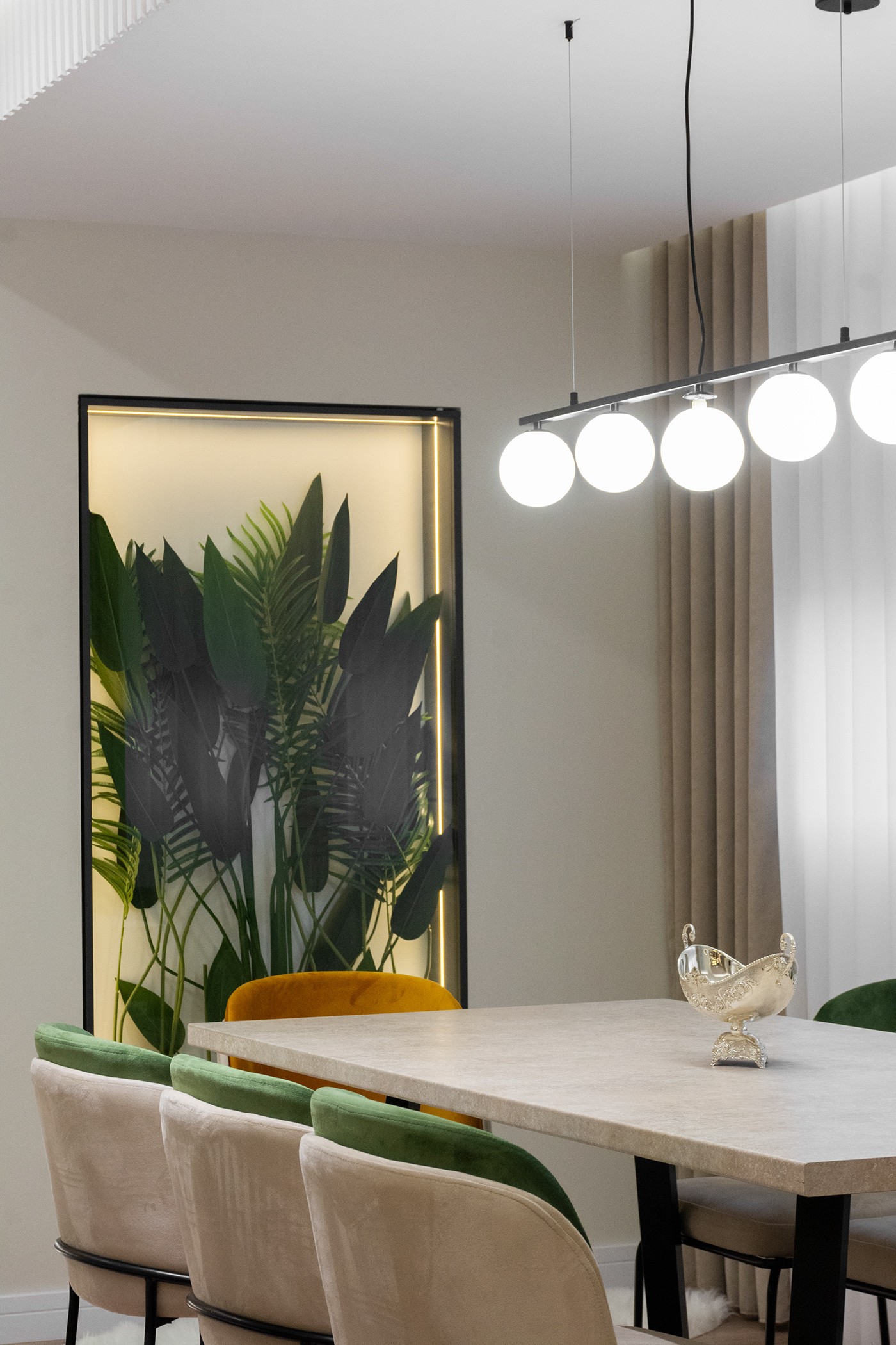 Dining table with green chairs and a backlit plant wall, apartment in Gostivar