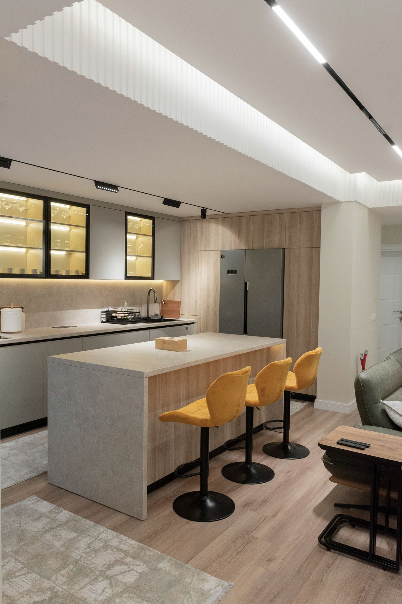 Kitchen with grey island, mustard bar stools and wood cabinets, apartment in Gostivar