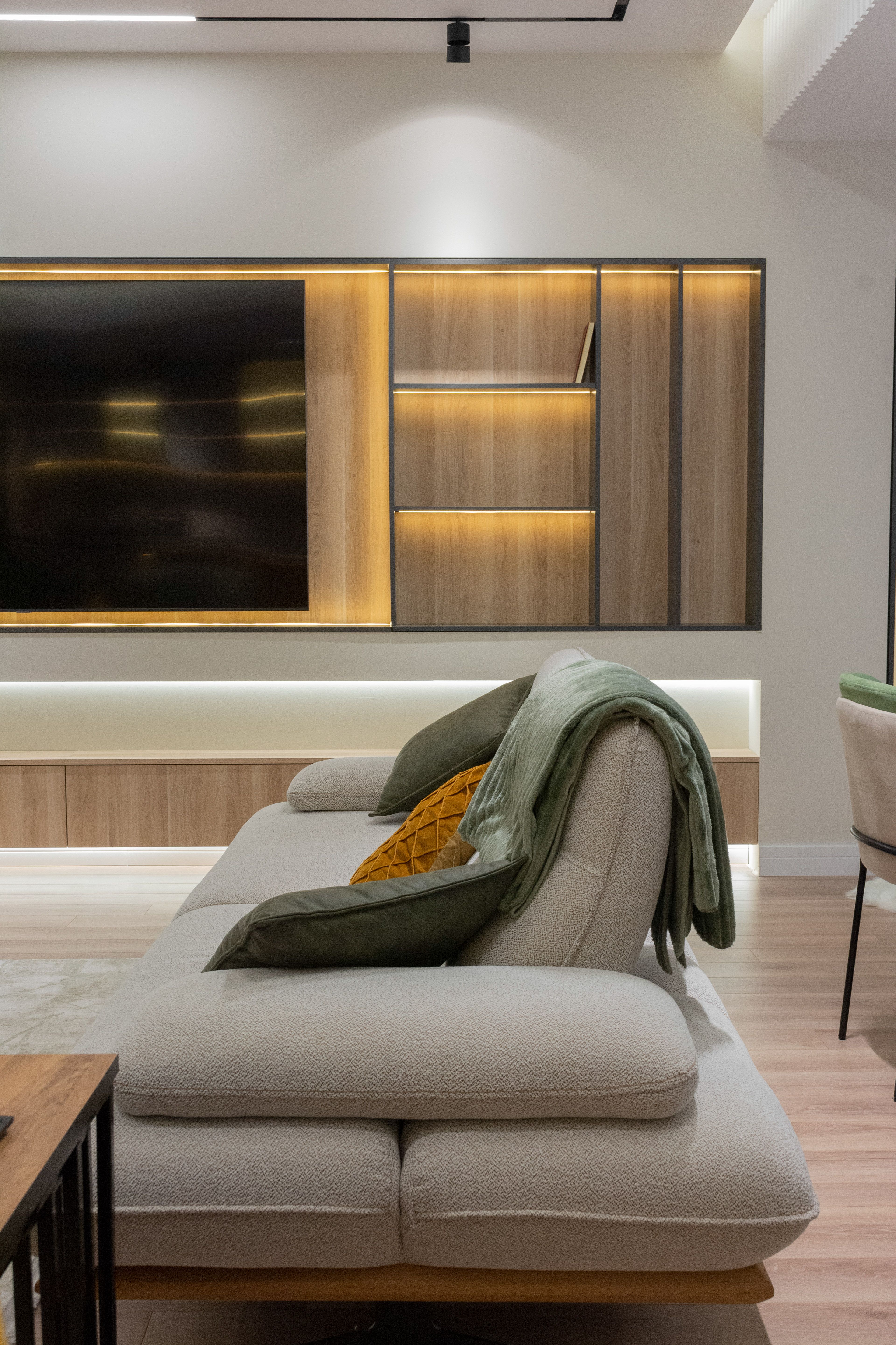 Wood TV unit with built-in lighting and beige sofa, apartment in Gostivar