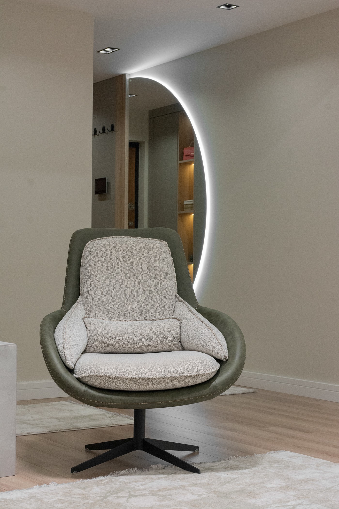 Green and white armchair in front of a backlit round mirror, apartment in Gostivar