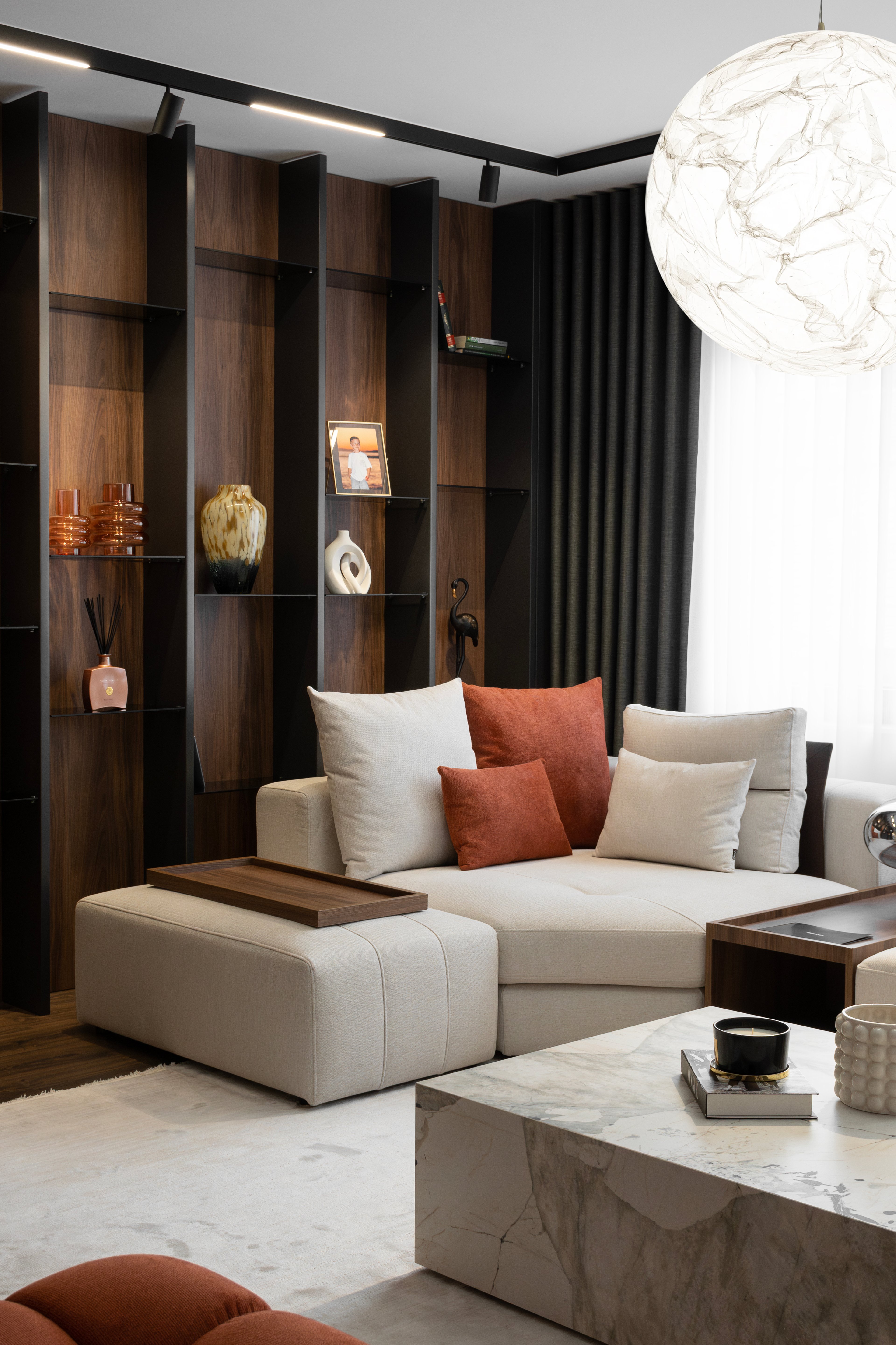 Living room with cream sofa, orange cushions and wood shelving, SZ apartment in Gostivar