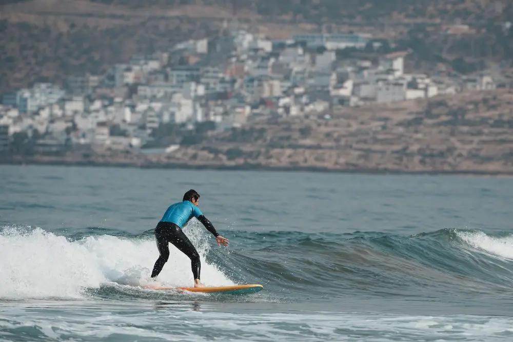 Beginner Surfer Riding a Wave - Surf Lessons Taghazout at The Yogi Surfer in Taghazout Bay, Morocco.