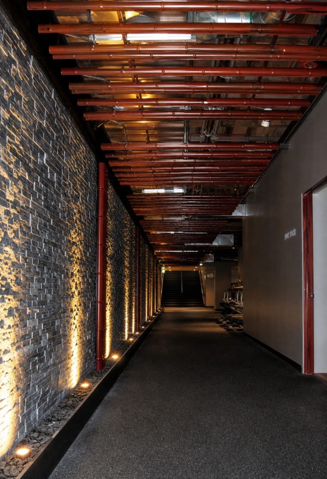 Stone wall corridor with bamboo ceiling installation at VIM Fitness, Cambridge