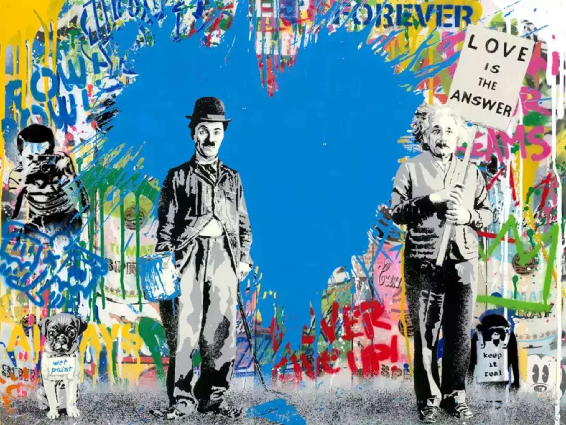 A graffiti-inspired artwork showcasing stencils of Charlie Chaplin and Albert Einstein side by side. Charlie Chaplin holds an open bucket of blue paint while Albert Einstein holds a picketed sign that reads 'LOVE IS THE ANSWER'. They both stand against a graffiti-covered wall adorned with collaged stencils and a prominently filled-in blue heart.