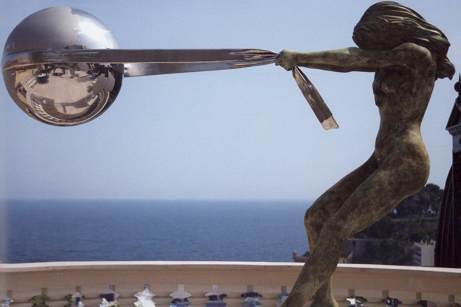 A bronze sculpture titled "The Force of Nature" depicting a large woman emerging from the earth, holding up a globe with her hands.