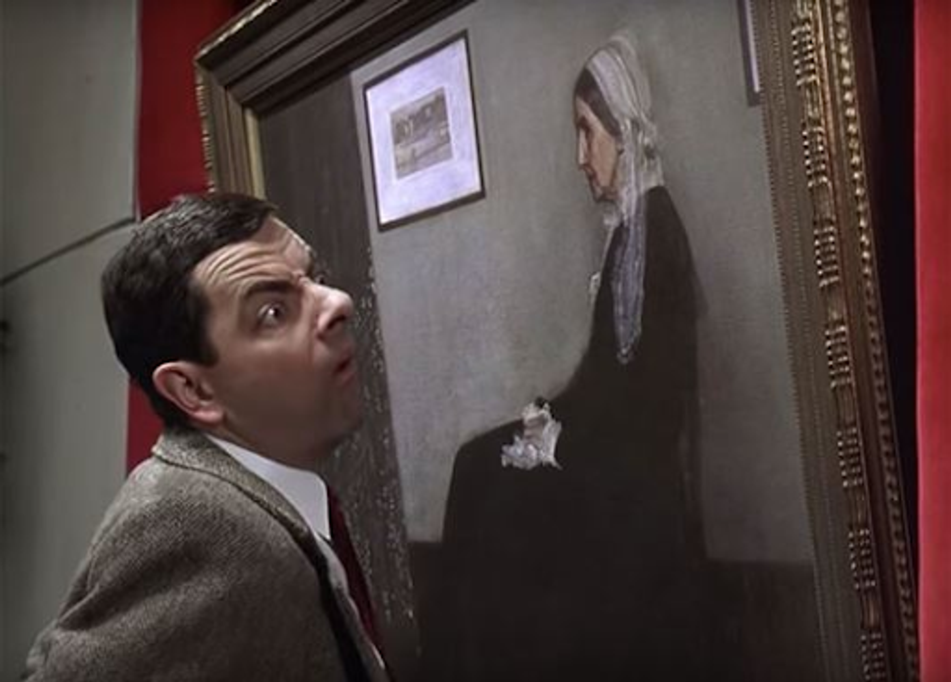 Photograph from the film production, Bean. A man closely staring at a fine art portrait.