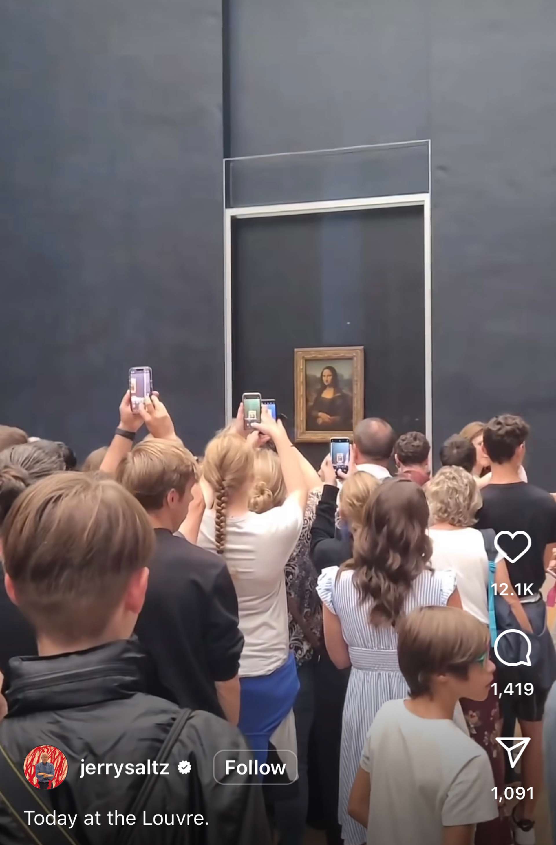 People holding up their smartphones to photograph the Mona Lisa inside the Louvre Museum. 