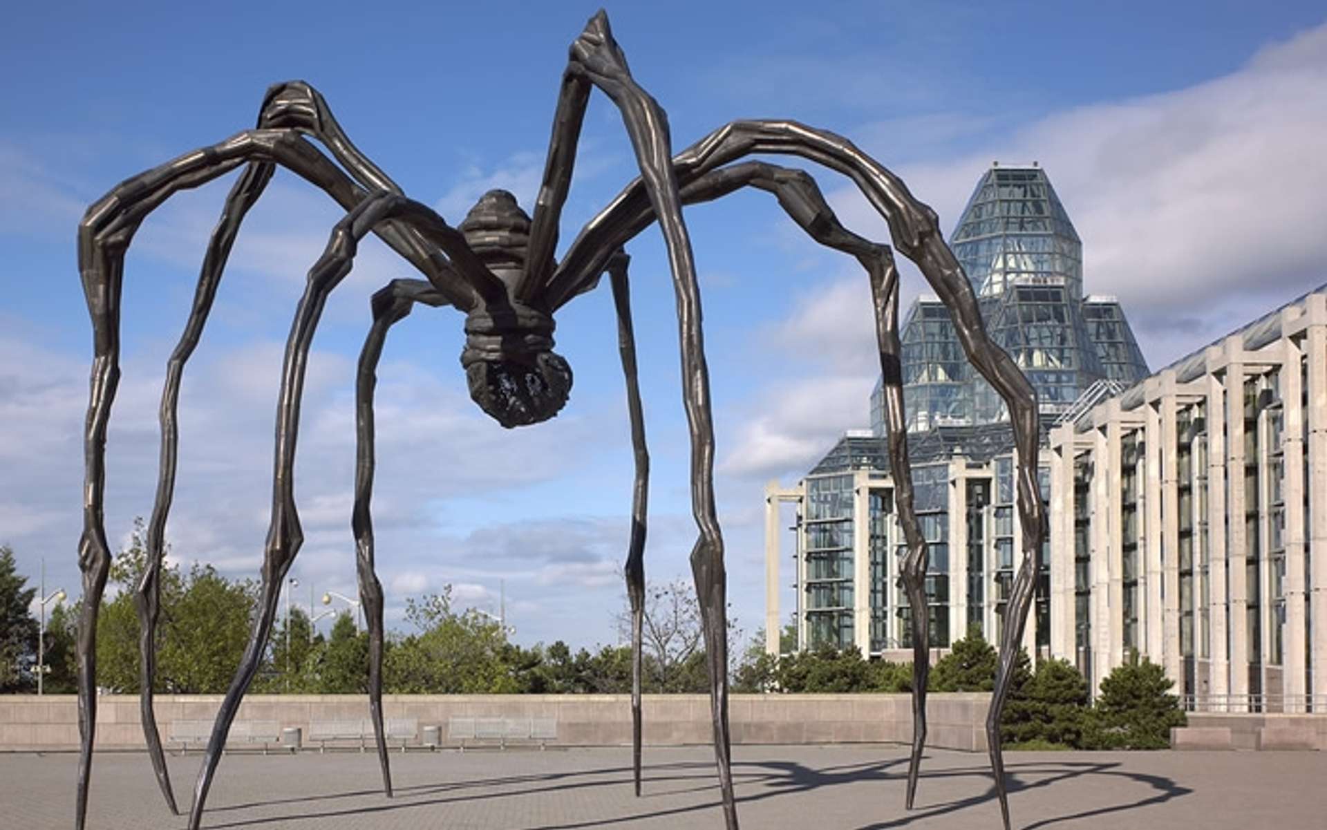 Sculpture of a black spider over thirty feet tall in front of a city landscape