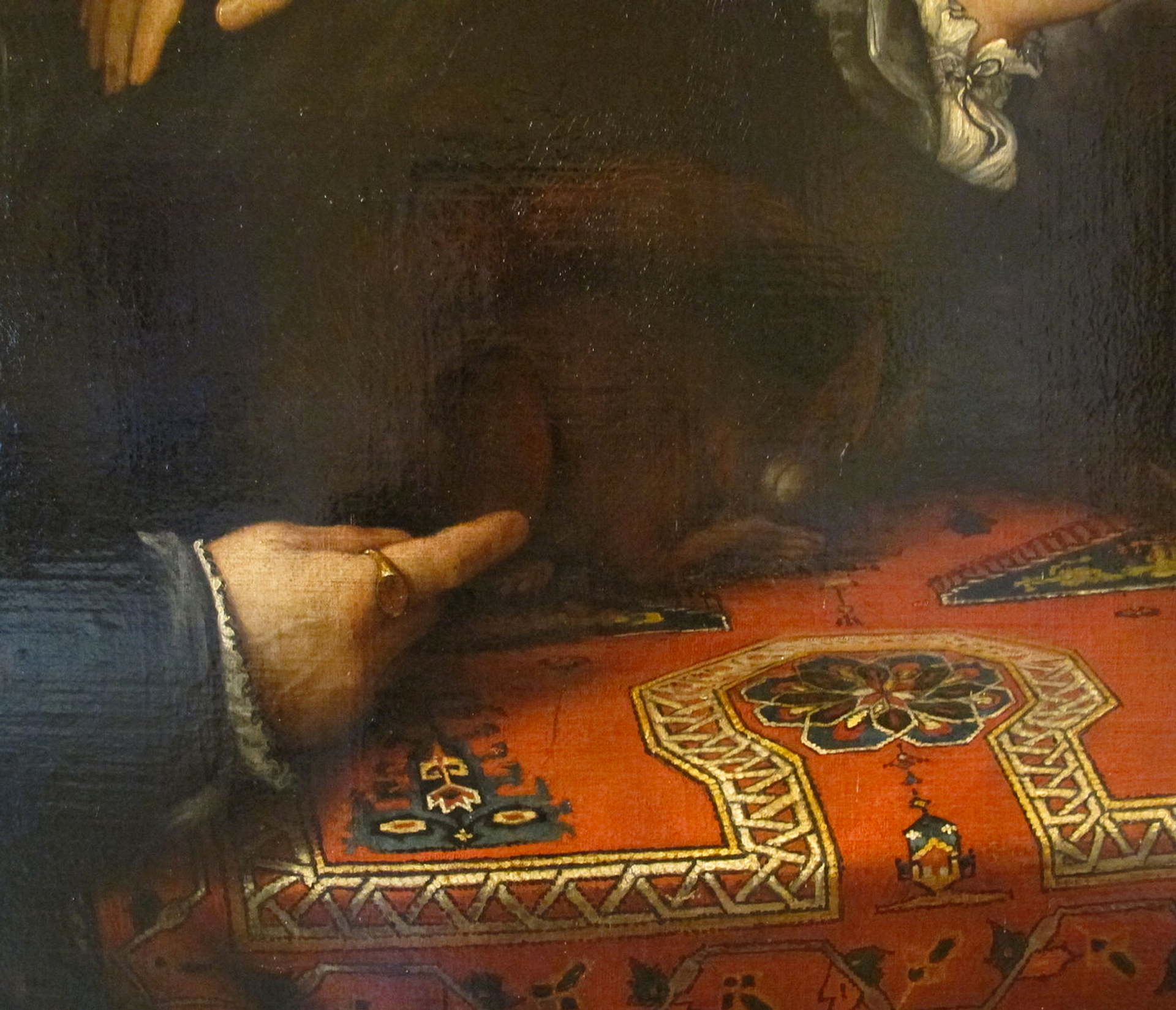 A close up of a Renaissance work by Lorenzo Lotto. It shows a man's hand resting on a bold patterned table cloth.