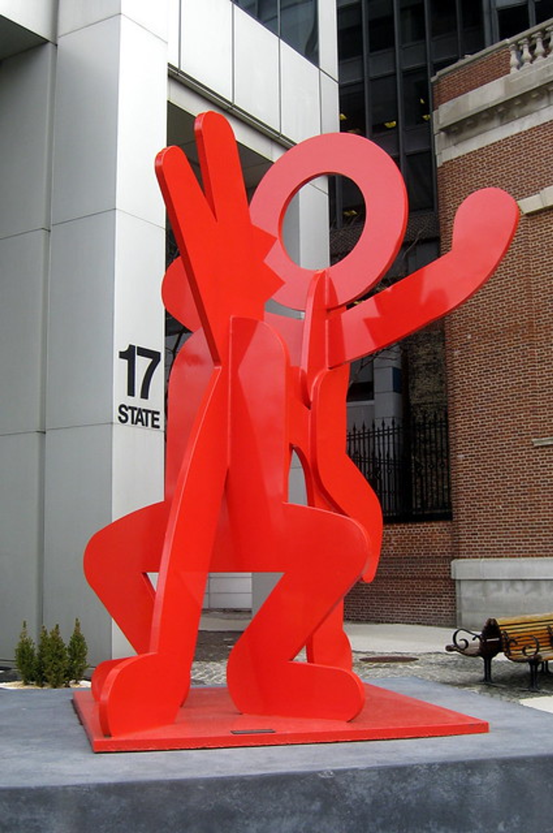 Keith Haring’s Untitled (Figure Balancing on Dog). An installation view of a red, painted steel sculpture of a human character on a dog. 