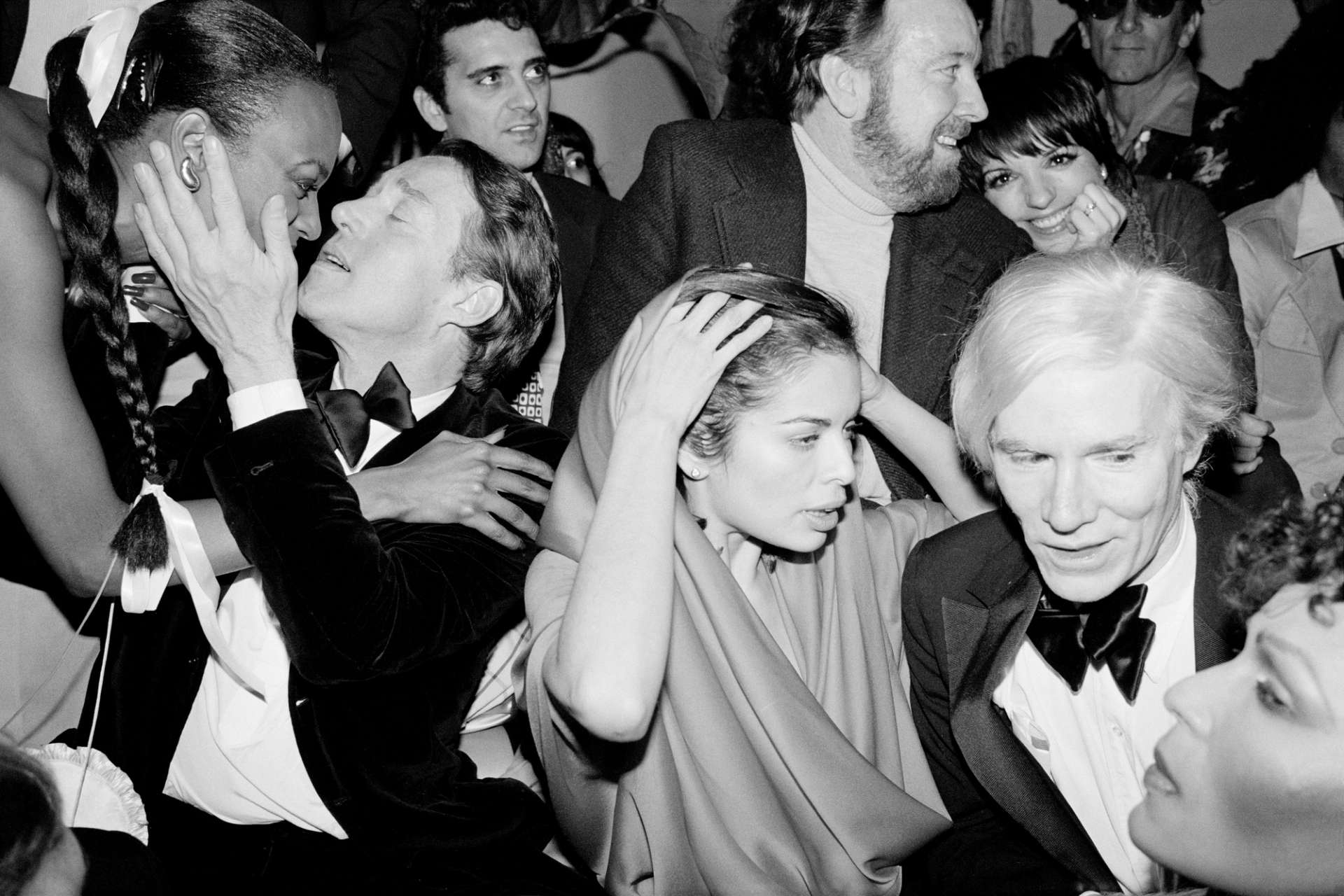 A black and white photograph by Robin Platzer showing Bianca Jagger, Halston, Liza Minnelli, Jack Halay Jr and Andy Warhol partying at Studio 54 at the centre of the frame
