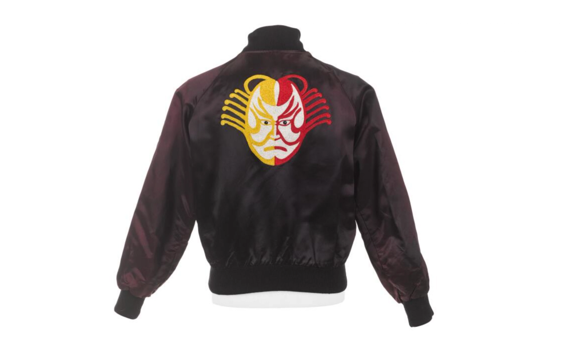 A two-tone black and mulberry satin bomber jacket embellished with a vivid appliquéd design of a Kabuki Actor’s head in densely embroidered yellow, scarlet and ivory silk thread.