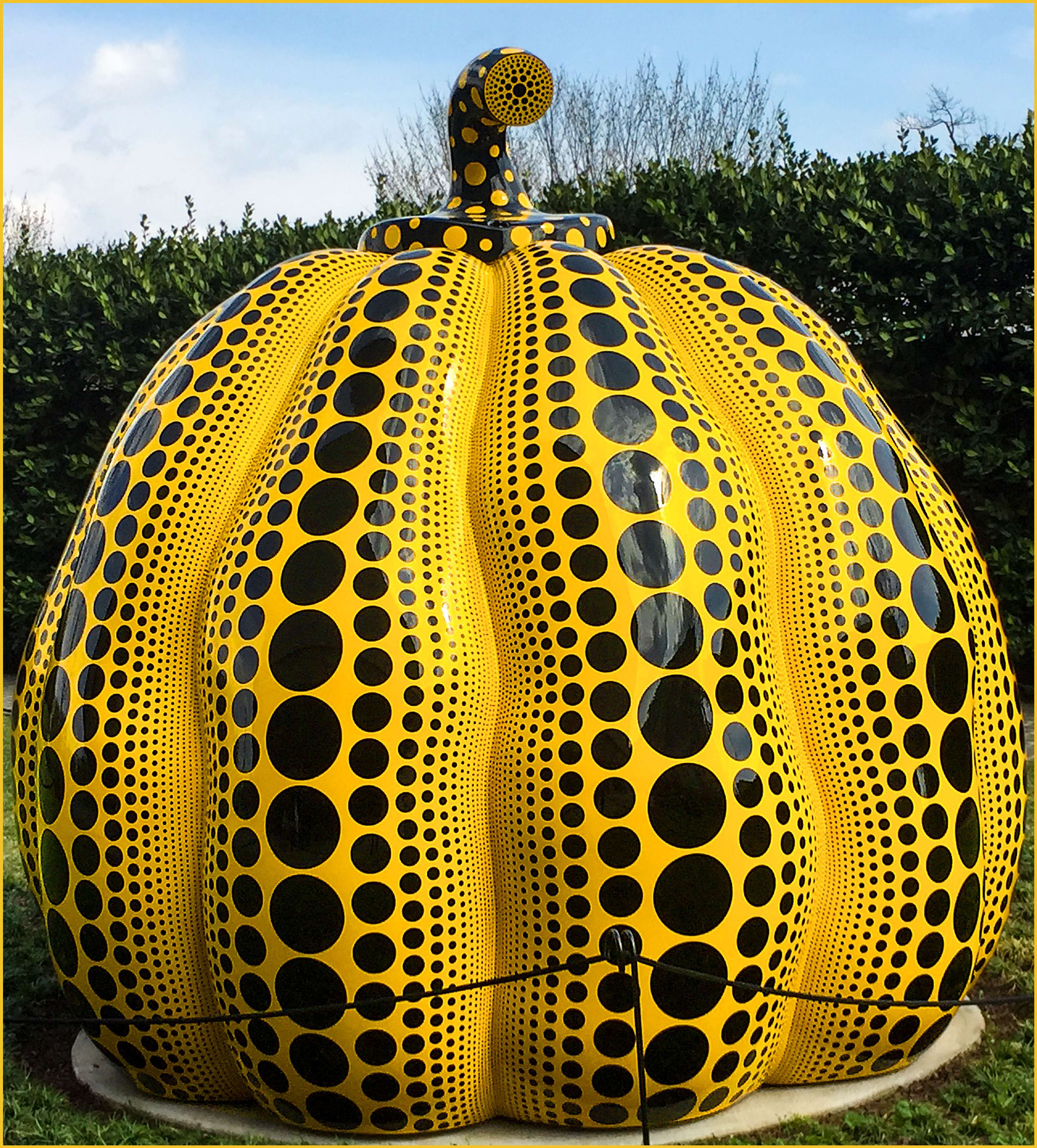 Image of large, yellow, polka dot pumpkin sculpture in a park