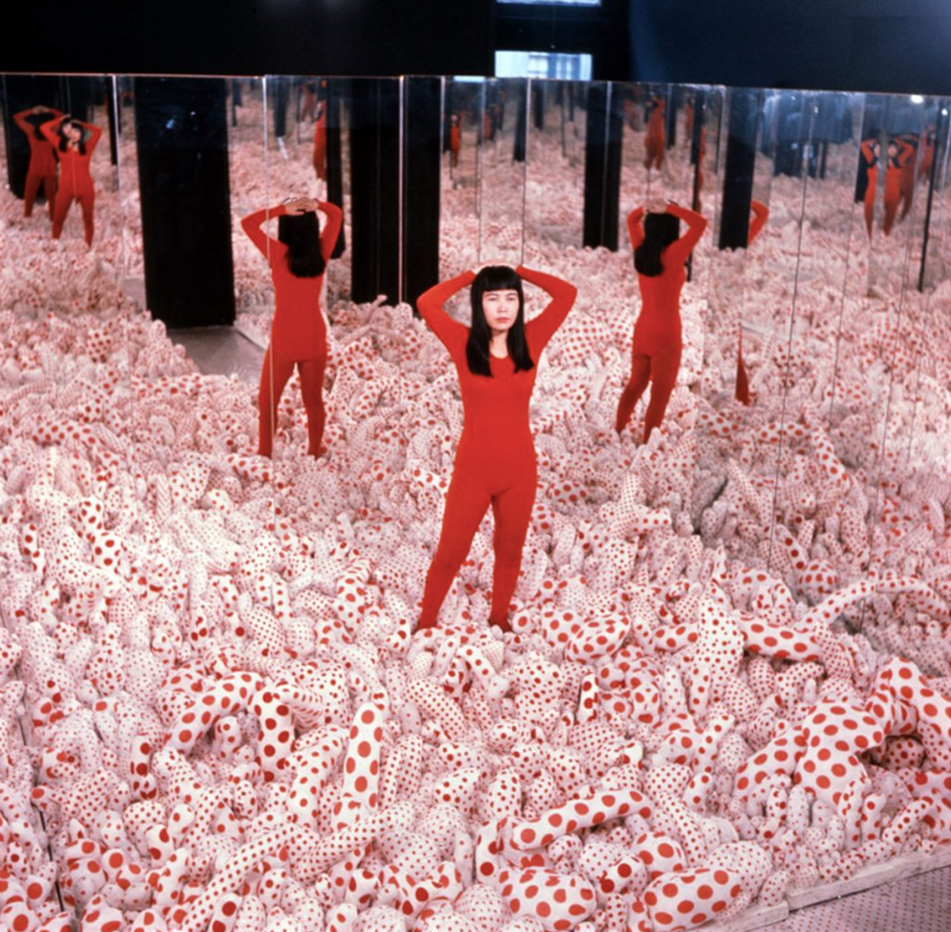 An installation artwork titled "Infinity Mirror Rooms" by Yayoi Kusama, featuring small rooms lined with mirrors, creating an infinite reflection of lights and shapes. Visitors immerse themselves in the kaleidoscopic experience.