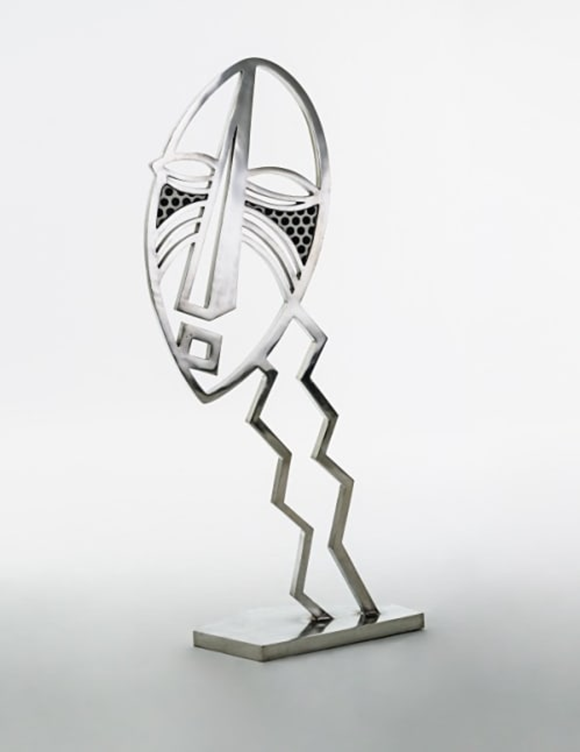 A large, metal sculpture of an African mask by Roy Lichtenstein.