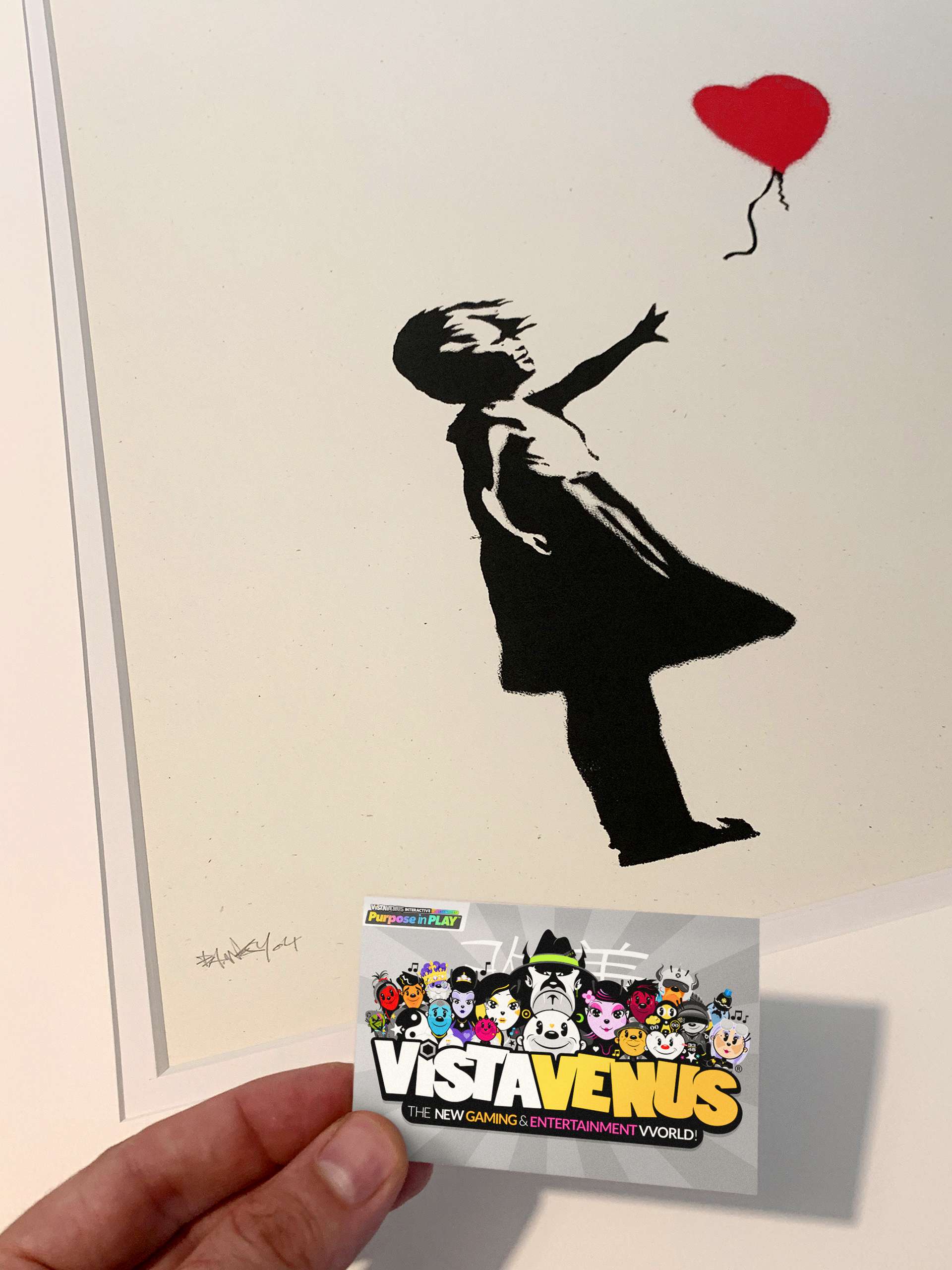 Vistavenus business card next to Banksy's Girl With Balloon signed print