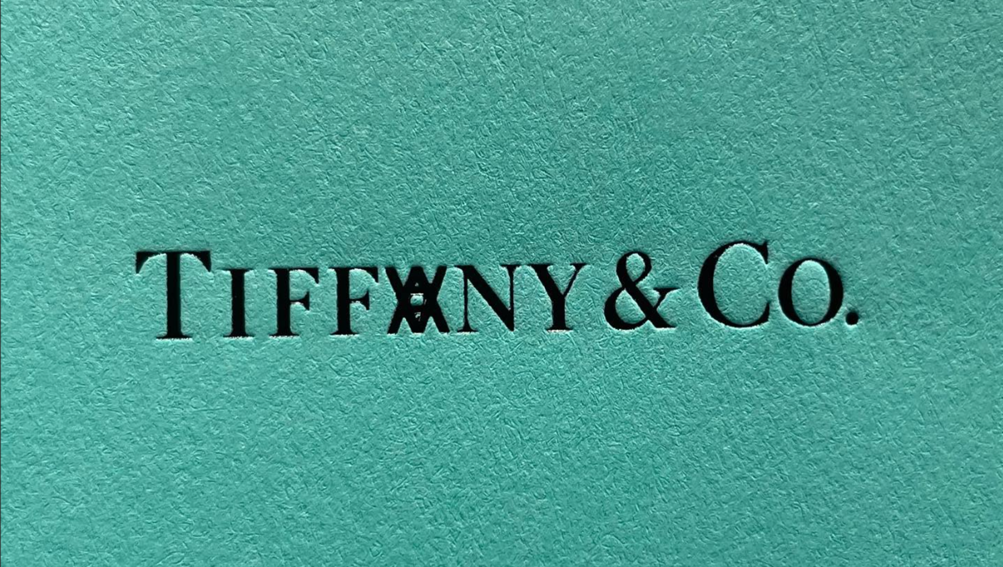 An image of the Tiffany & Co logo against the iconic duck egg blue background, but the letter A is replaced by Daniel Arsham's logo.