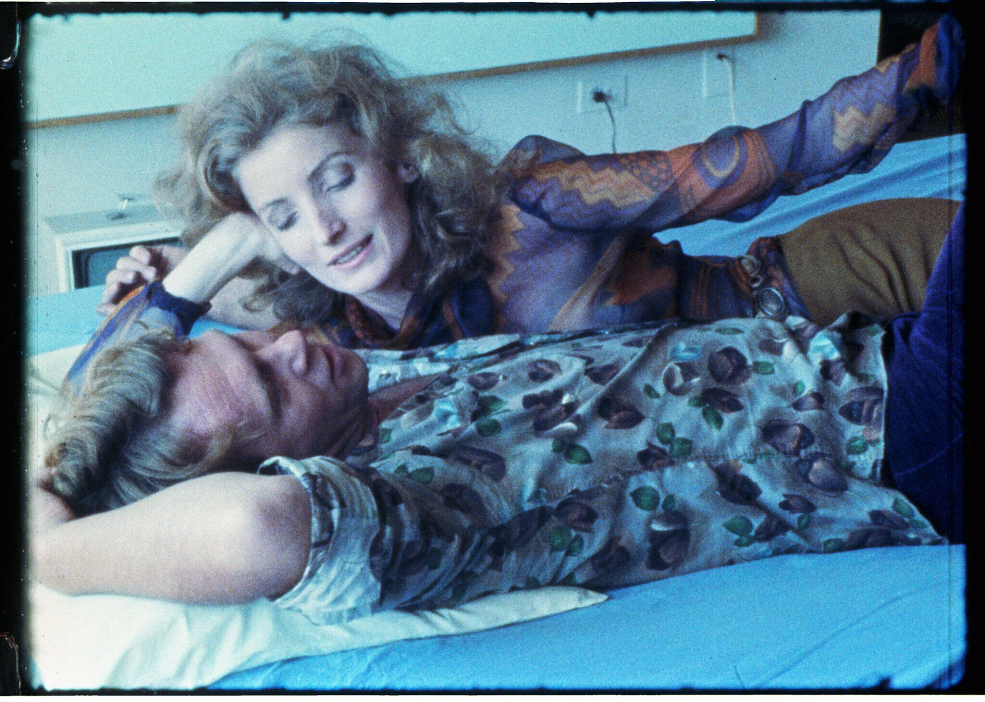 An image from Andy Warhol's Blue Movie film. It shows a couple lying on a bed, as the woman gazes into the man's face.