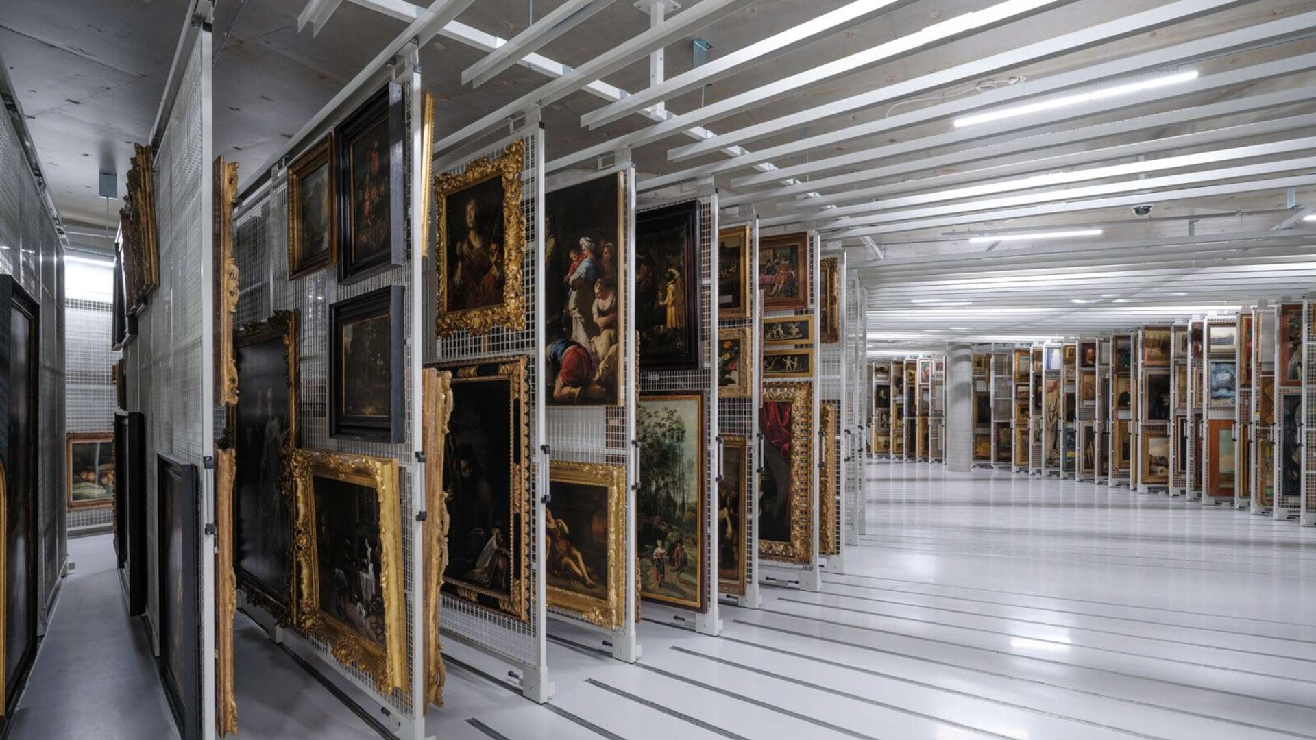 Paintings in gold frames stored in a curved archival storage system