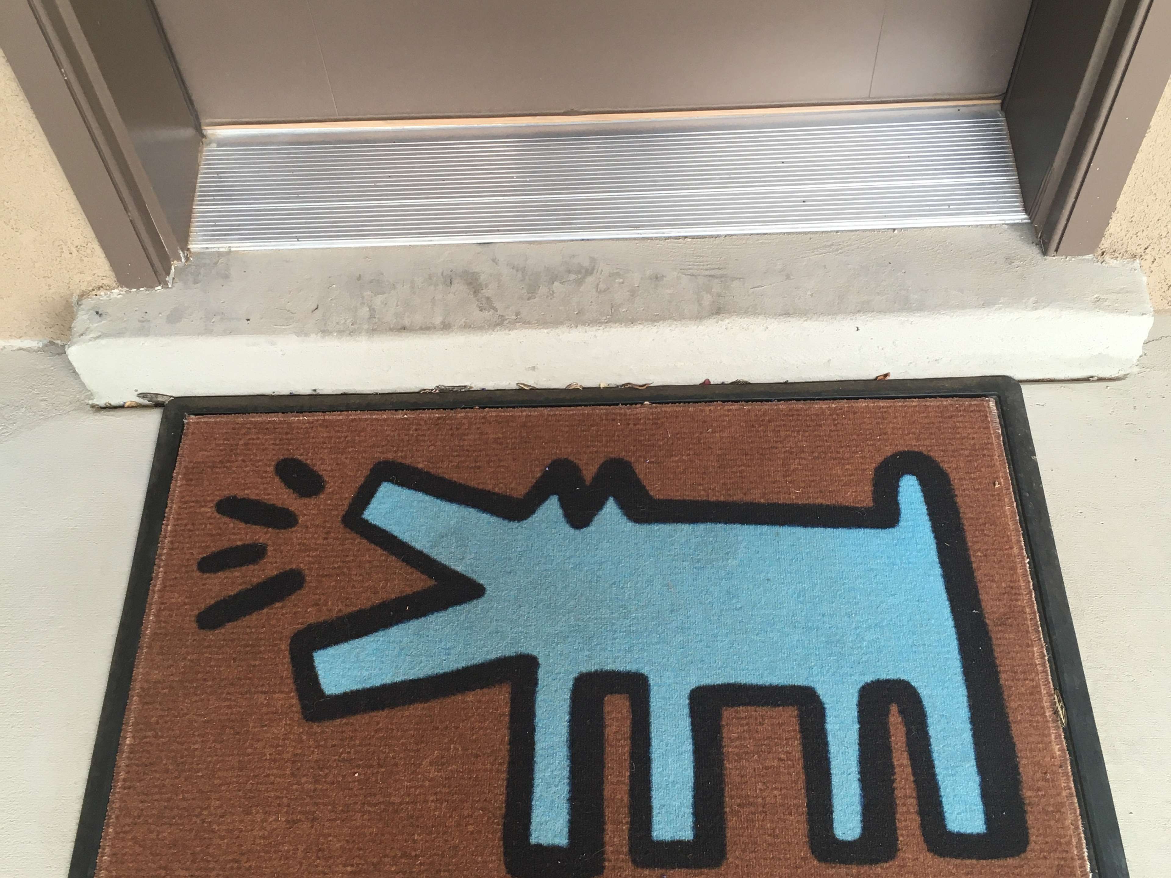 A doormat containing an image of Keith Haring's Barking Dog, in blue