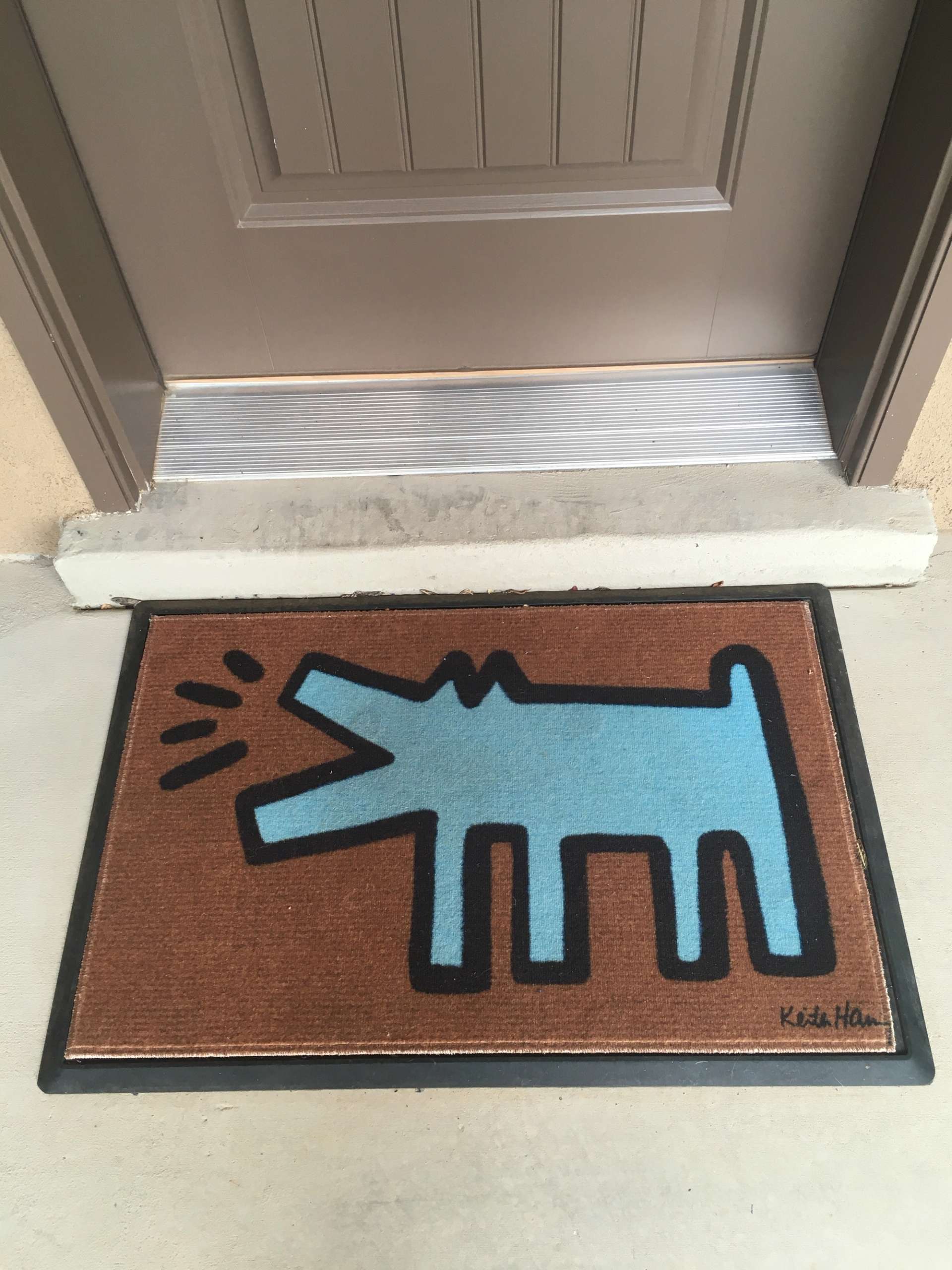 A doormat containing an image of Keith Haring's Barking Dog, in blue