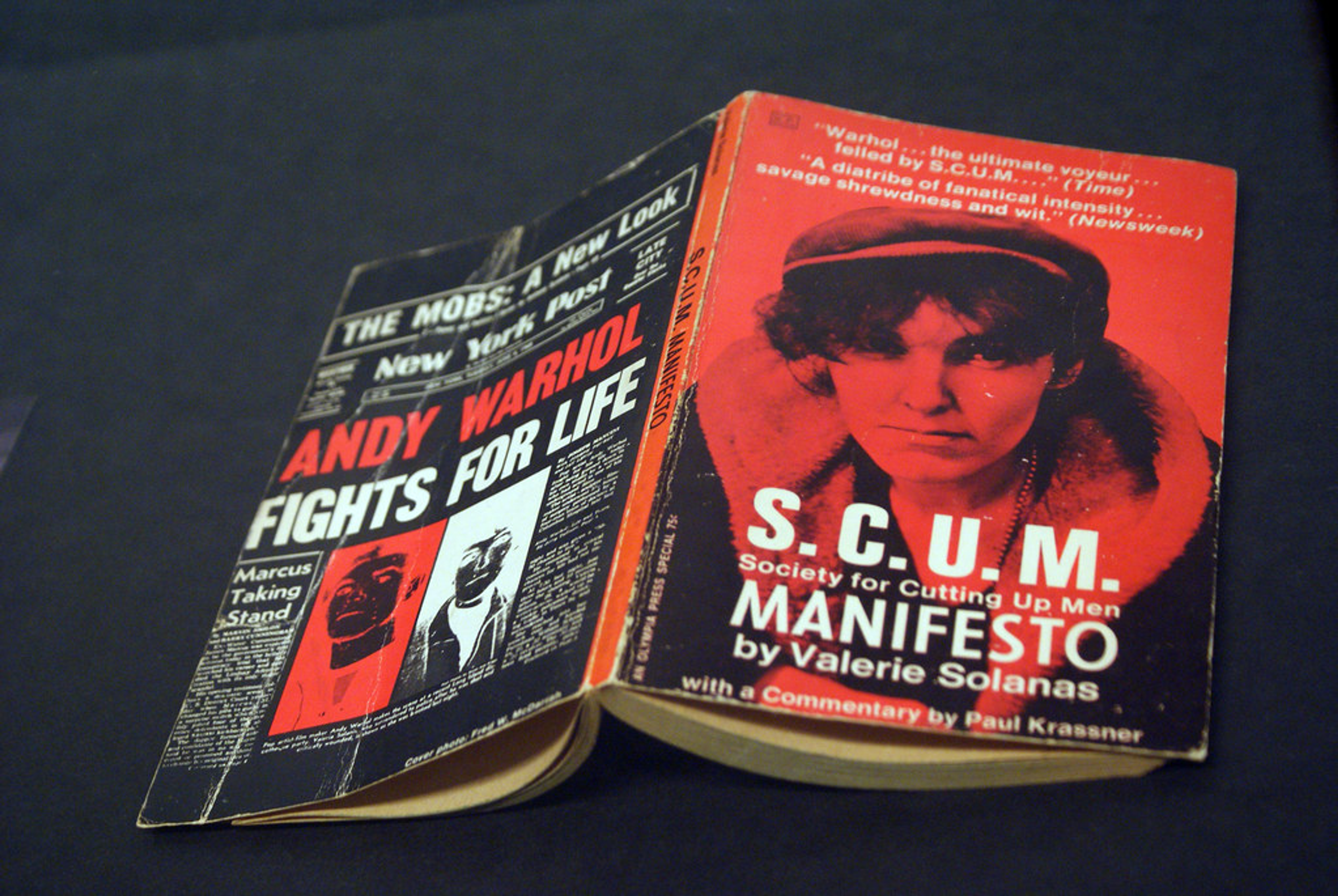 This image shows the front and back cover of Solana's book, SCUM Manifesto. The author is shown on the front cover, while the headline "Andy Warhol fights for life" is on the back.