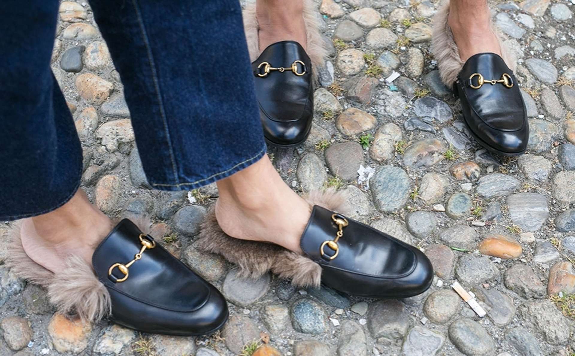 An image of two pairs of feet clad in Gucci horsebit loafers.