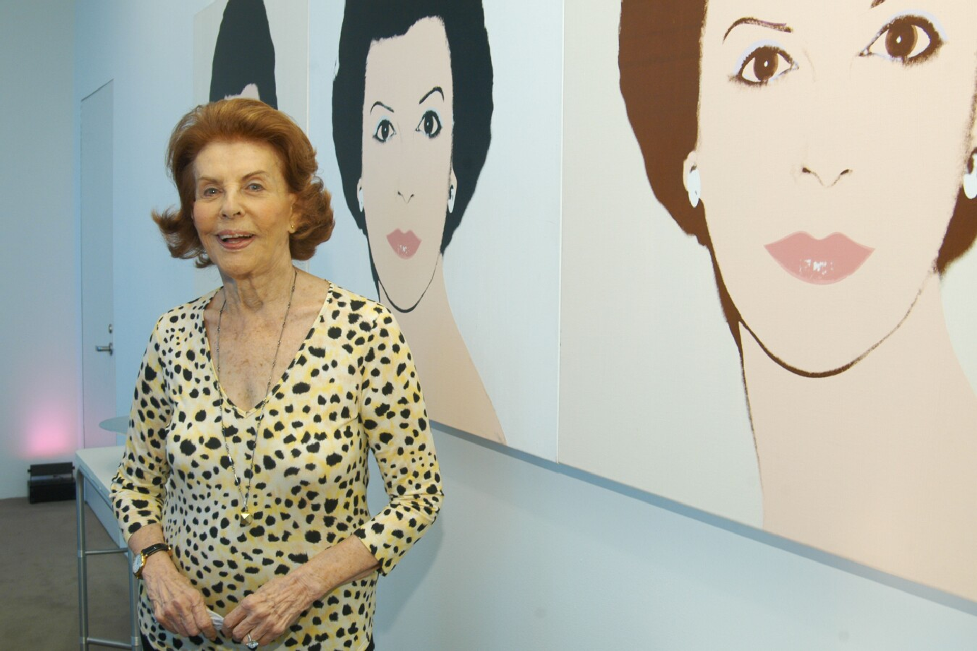 This photograph shows Emily Fisher Landau in front of a series of portraits done of her by Andy Warhol.