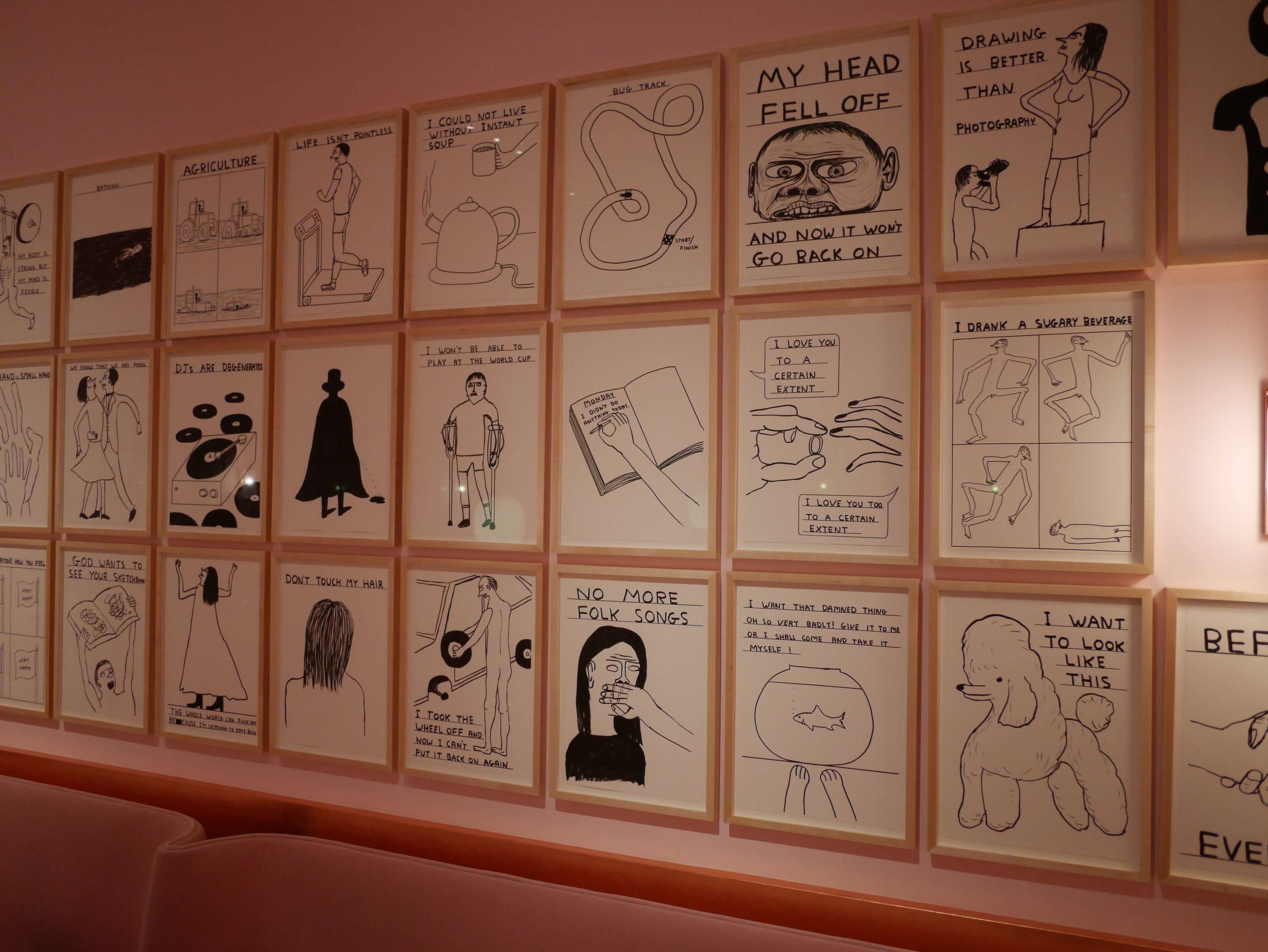Dozens of prints by David Shrigley are seen hanging on a pink wall at the restaurant Sketch.