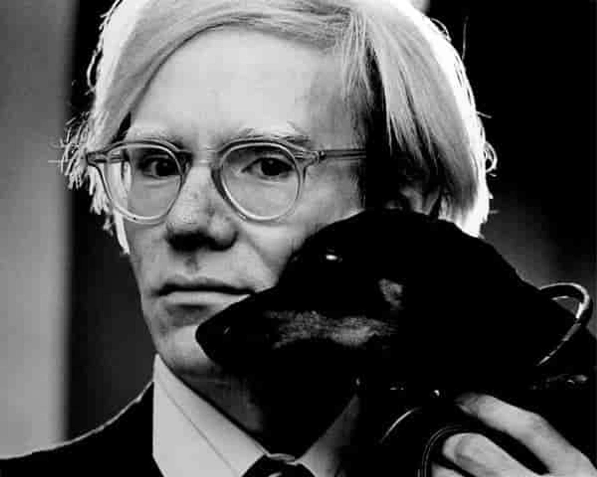 Black and white photograph of Andy Warhol holding a dog