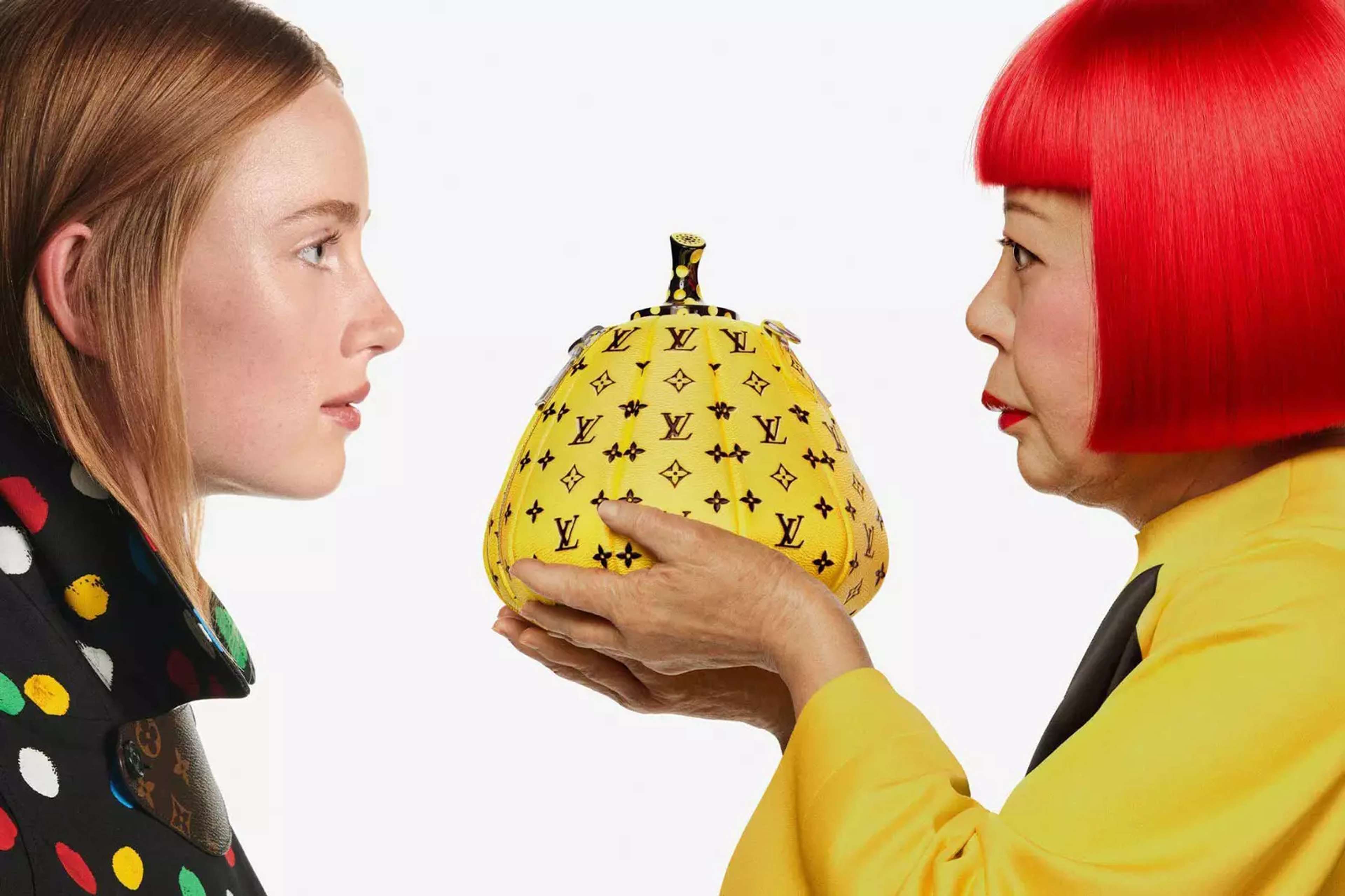 A photo of two women facing each other with one holding a yellow pumpkin-shaped bag with the black Louis Vuitton monogram over it between their faces