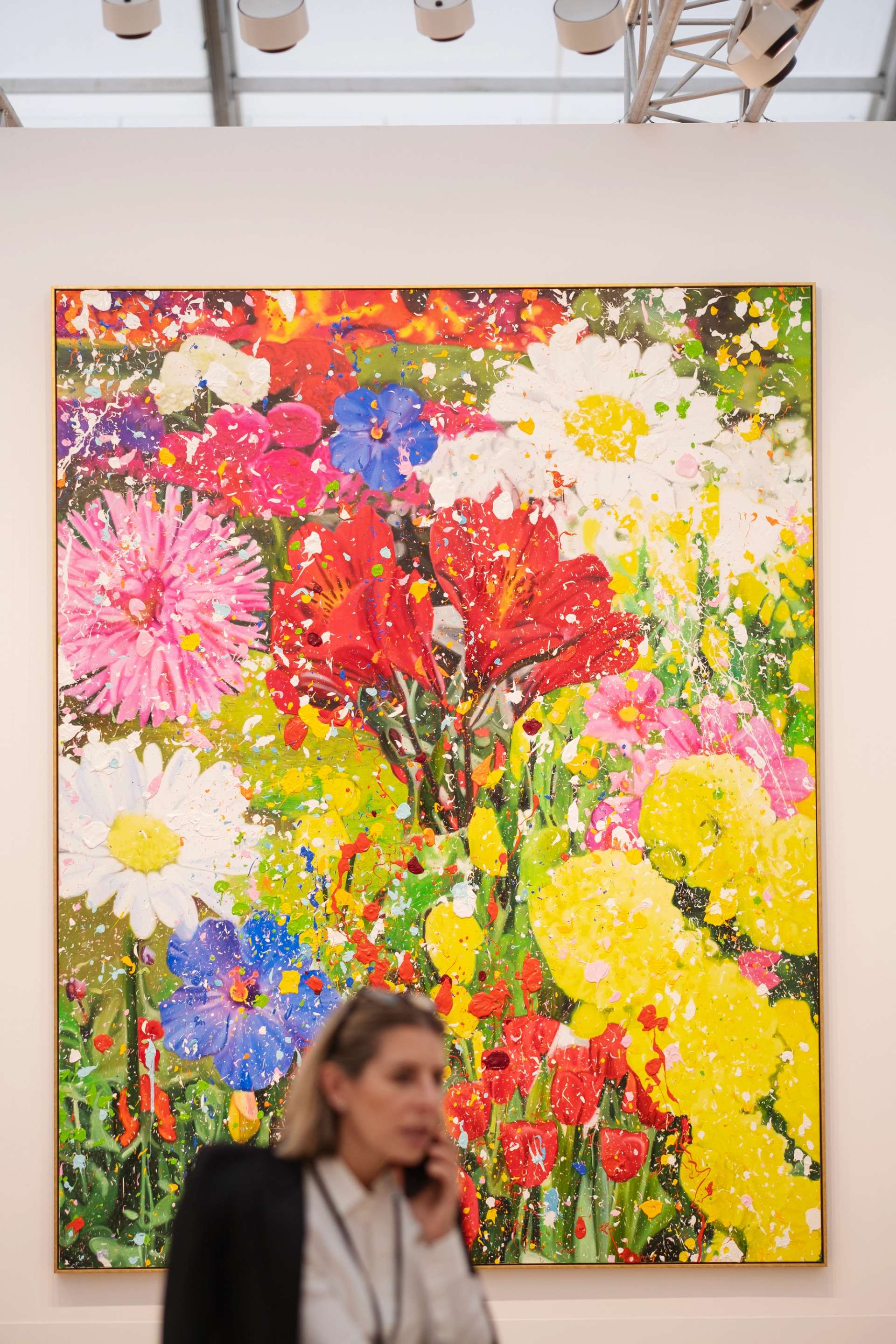Image of a woman standing before a large Damien Hirst painting showcased at the Gagosian booth during Frieze London 2023.